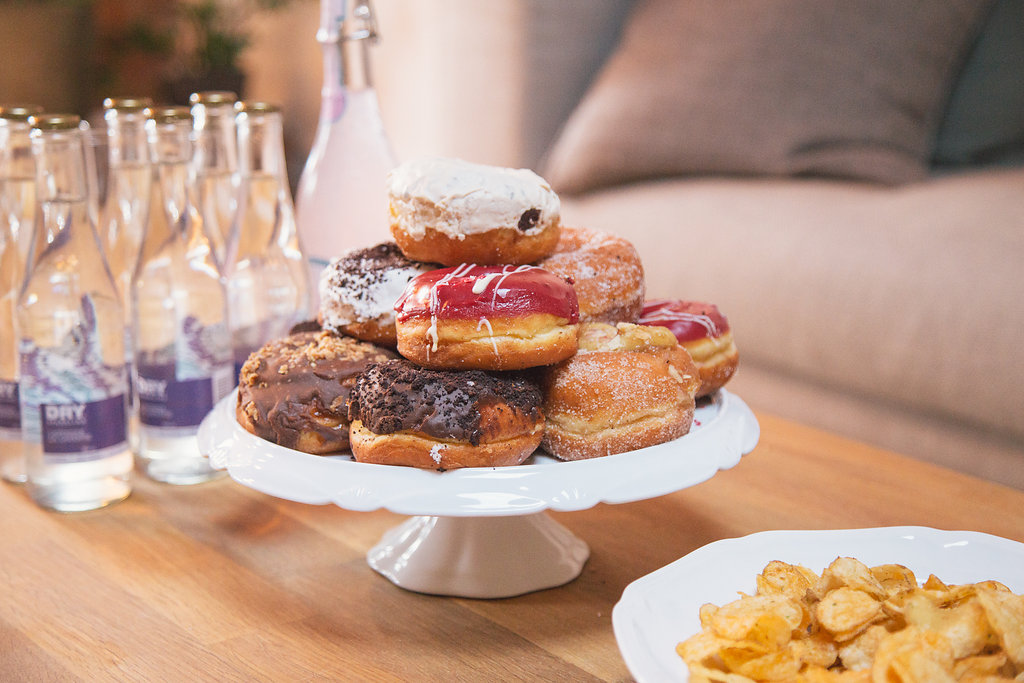 Doughnuts on a pedestal with bottled beverages in the background and a bowl of chips beside